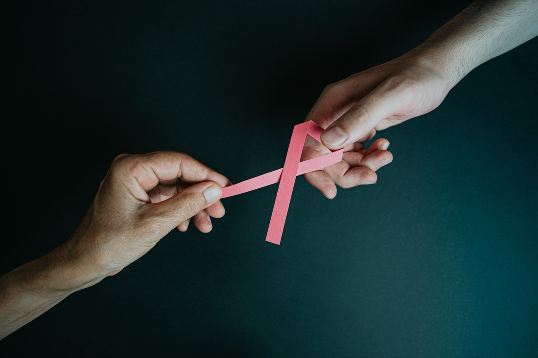 Top View of Hands Holding Breast Cancer Pink Paper Ribbon
